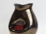 a small black vase with a red glass inside of it