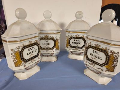 trois boîtes blanches et dorées, munies d'étiquettes, posées sur une table bleue