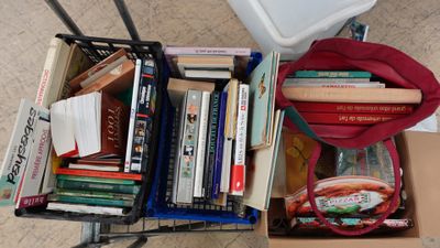 un chariot rempli de livres posé par terre à côté des toilettes