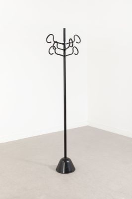 une photo d'un porte-manteau en métal noir sur lequel sont accrochés trois manteaux