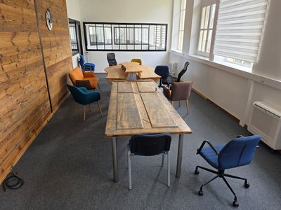 tables and chairs in a room with a wooden wall and windows