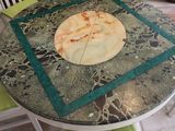 a table with a pizza on top of it on a tiled floor