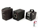 three old cameras sitting next to each other on a white surface