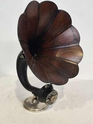 un vieux gramophone posé sur un support, devant un fond blanc