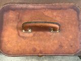 a brown suitcase with a handle sitting on the ground