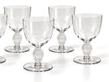 six verres à vin transparents empilés les uns sur les autres sur une surface blanche
