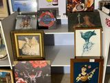 de nombreuses photos et peintures posées sur une étagère dans une pièce