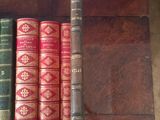 several old books are lined up on a shelf on a table