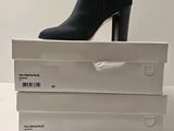a pair of black boots sitting on top of a stack of white boxes