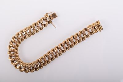 gros plan d'un bracelet en chaîne en or sur une surface blanche