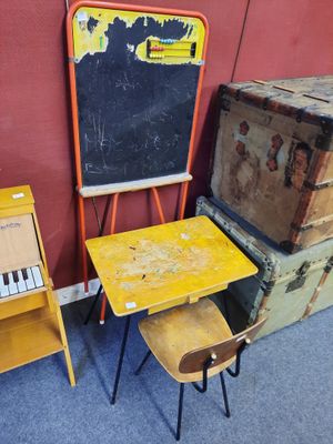 un petit bureau et une chaise dans une salle équipée d'un tableau noir