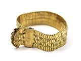 gros plan d'un bracelet en or sur une surface blanche