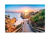 a wooden walkway going down to the beach at sunset