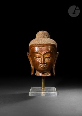 une image représentant une tête de Bouddha en bois posée sur un socle
