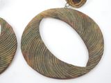 two pairs of earrings with a circular design on them on a white surface