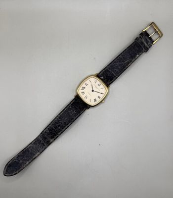 gros plan d'une montre sur une surface blanche avec un bracelet noir
