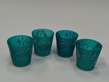 quatre verres bleus ornés de motifs dorés, posés sur une surface blanche