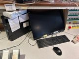 a desk with a computer, keyboard, mouse, and other electronics on it