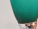 a green glass vase with a silver base on a table