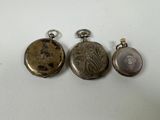 three different types of pocket watches on a white surface