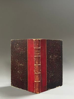 an old book sitting on top of a white table next to a red book