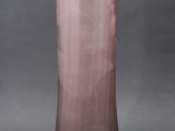 purple glass vase on a gray surface with a black background