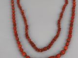 a red beaded necklace with a gold clasp on a white background