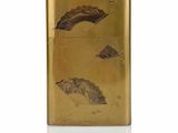 an image of a gold lighter with a leaf design on it