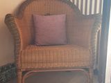 une chaise en osier avec un coussin rose dans un coin de la pièce
