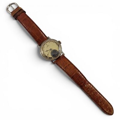gros plan d'une montre sur une surface blanche avec un bracelet marron