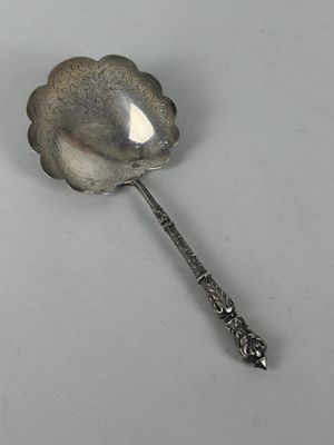 a silver spoon with a flower on it on a white surface