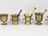 plusieurs types de mortiers en laiton et d'autres objets posés sur une surface blanche