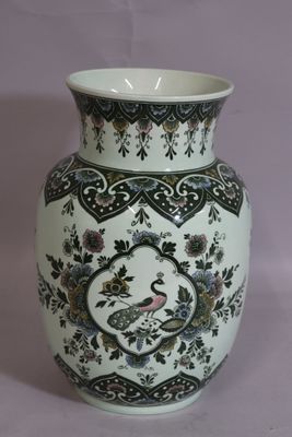 a white vase with a peacock on it on a table