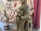 a statue of a woman sitting on a table next to a clock