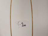 gros plan d'un collier en or sur une surface blanche