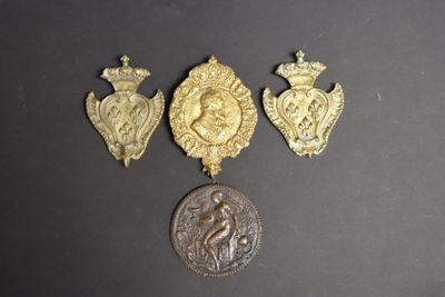 trois médailles d'or et une pièce de monnaie posées sur un fond noir