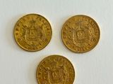 three gold coins sitting on top of a white surface