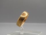 a close up of a gold wedding ring on a clear square
