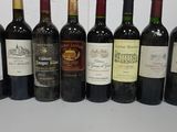 bottles of wine lined up on a table in front of a red wall