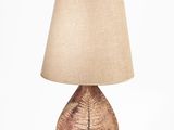 un gros plan d'une lampe posée sur un socle blanc, avec un abat-jour marron