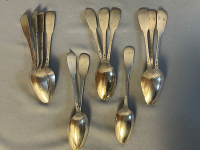 six silver spoons are arranged in a row on a table