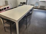 a long table with chairs and a refrigerator in the room