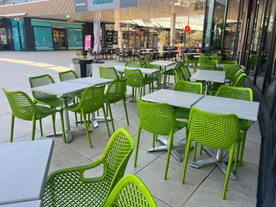 de nombreuses chaises et tables vertes à l'extérieur d'un restaurant