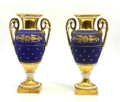 une paire de vases bleus et dorés posés sur une surface blanche