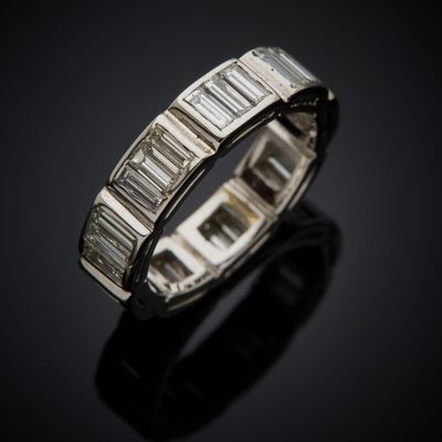 a white gold ring with baguets of diamonds on a black surface