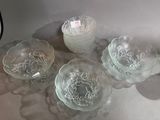 four glass bowls sitting on a table with a candle