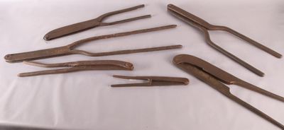 Six paires de pinces sont posées sur une table recouverte d'une nappe blanche.