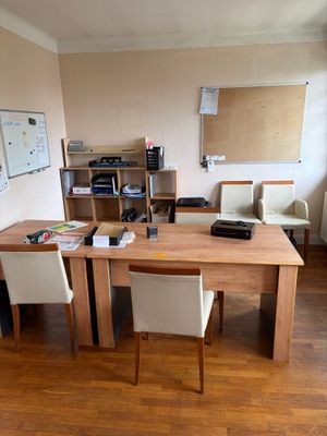 une table en bois avec deux chaises et un bureau sur lequel se trouve une imprimante