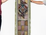 two men standing next to a tall stained glass window