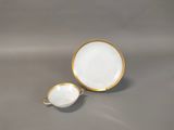 a white and gold cup and saucer on a gray surface